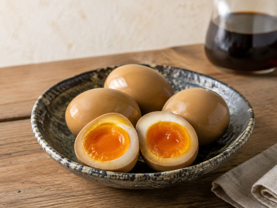 Halved marinated ramen eggs with jammy yolks served in a ceramic ramen bowl.